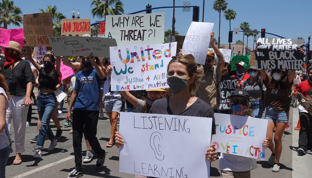 Oceanside, CA / USA - June 7, 2020: People hold signs during peaceful Black Lives Matter protest march. One reads `United We Stand`.